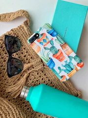 Lifestyle goods including stylish water bottles, tech accessories, and eco-friendly tote bags displayed on a wooden table.