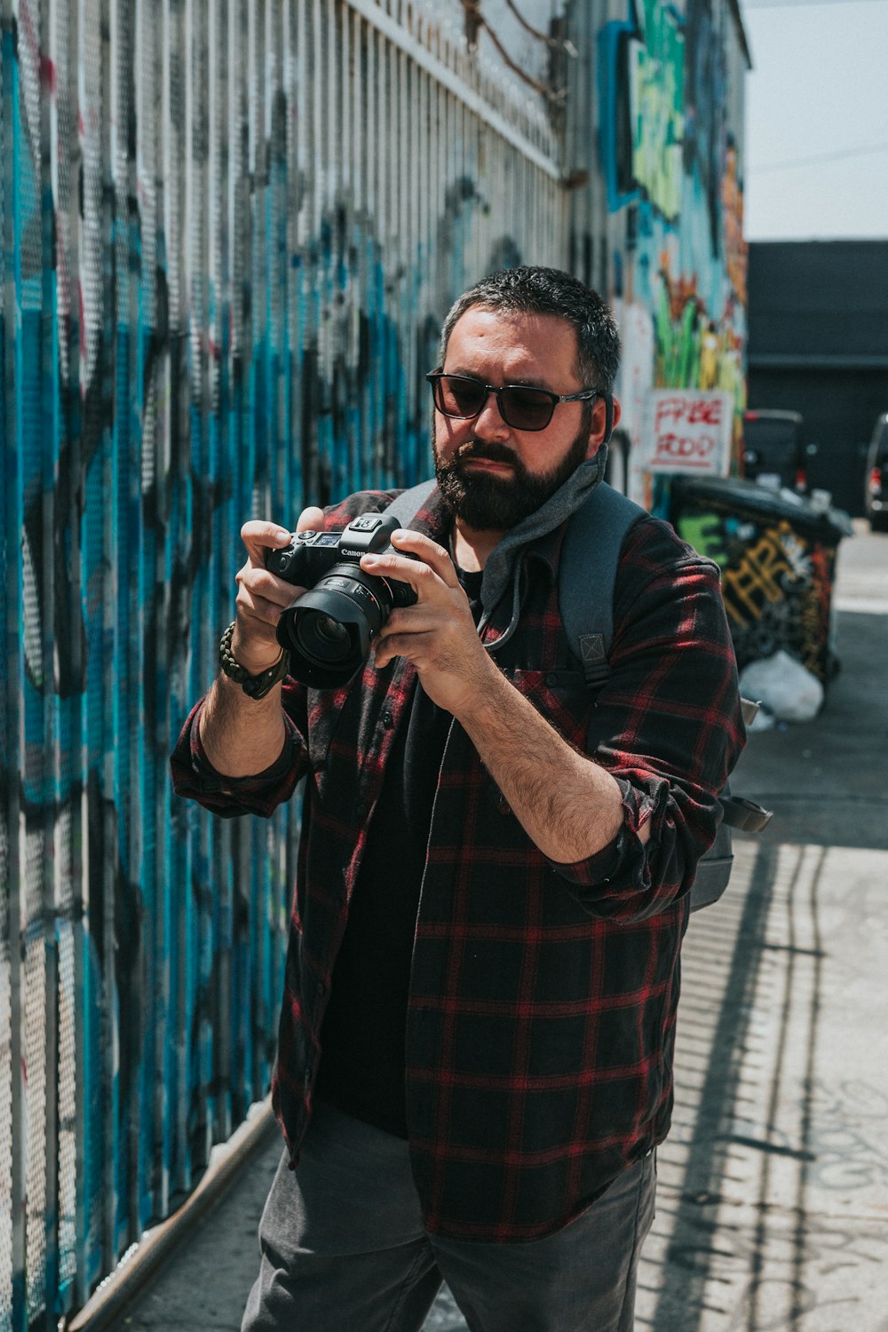 man in red and black plaid dress shirt holding black dslr camera