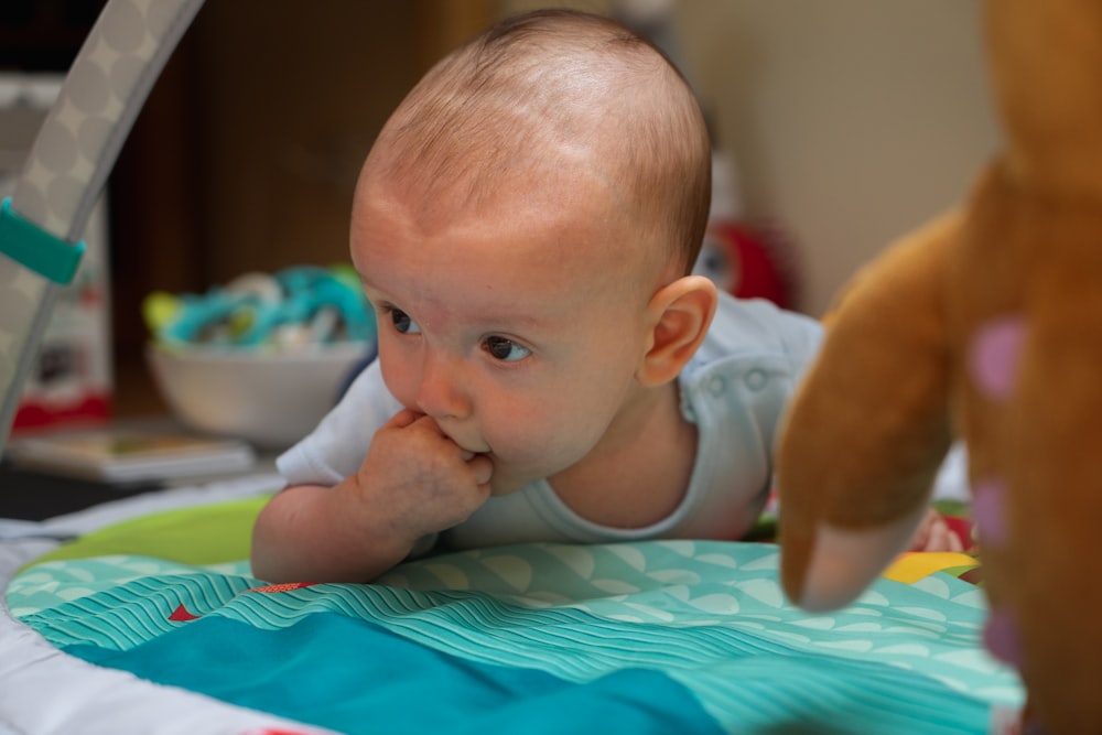 baby in blue tank top on white and green bed