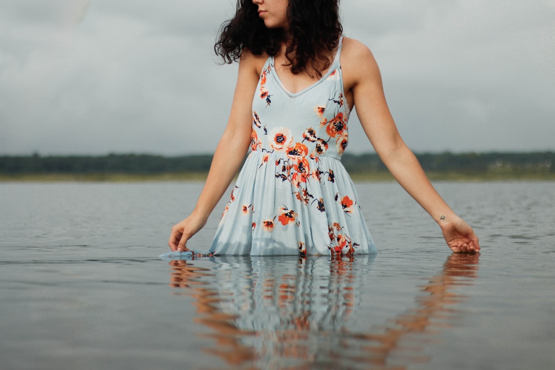 woman in white red and green floral dress standing on water during daytime