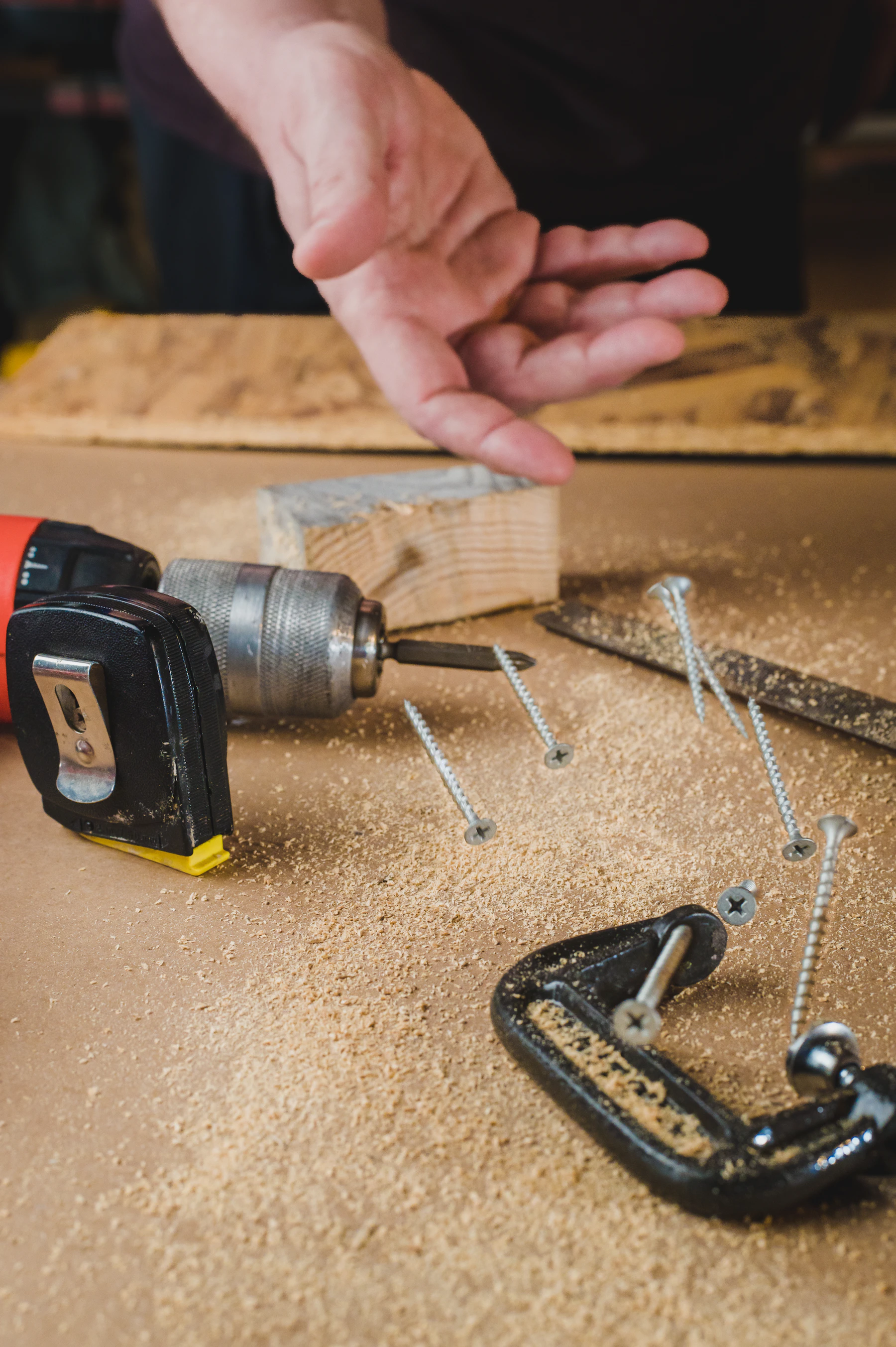 Cordless drill, screws and hand tools arranged on a woodworking bench