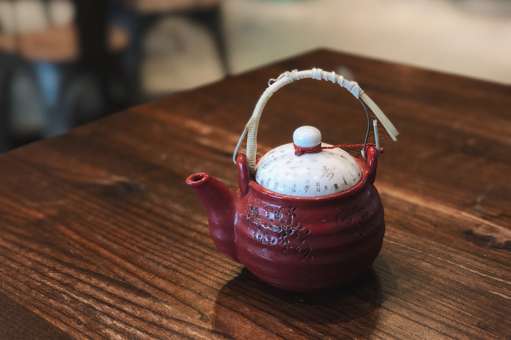 red ceramic teapot on brown wooden table