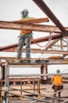 man in blue denim jeans and blue denim jacket standing on orange metal bar during daytime