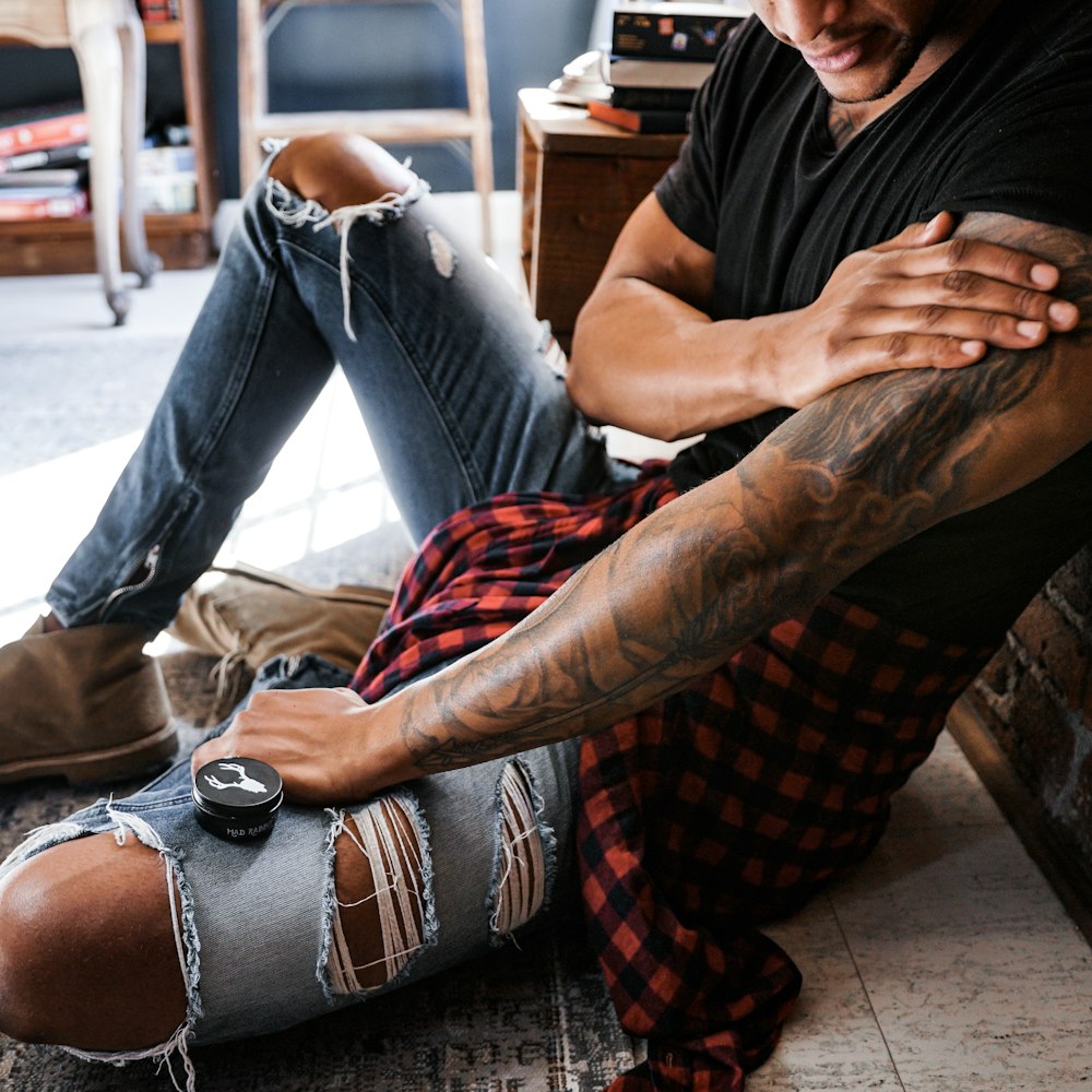 man in black t-shirt and blue denim jeans sitting on chair