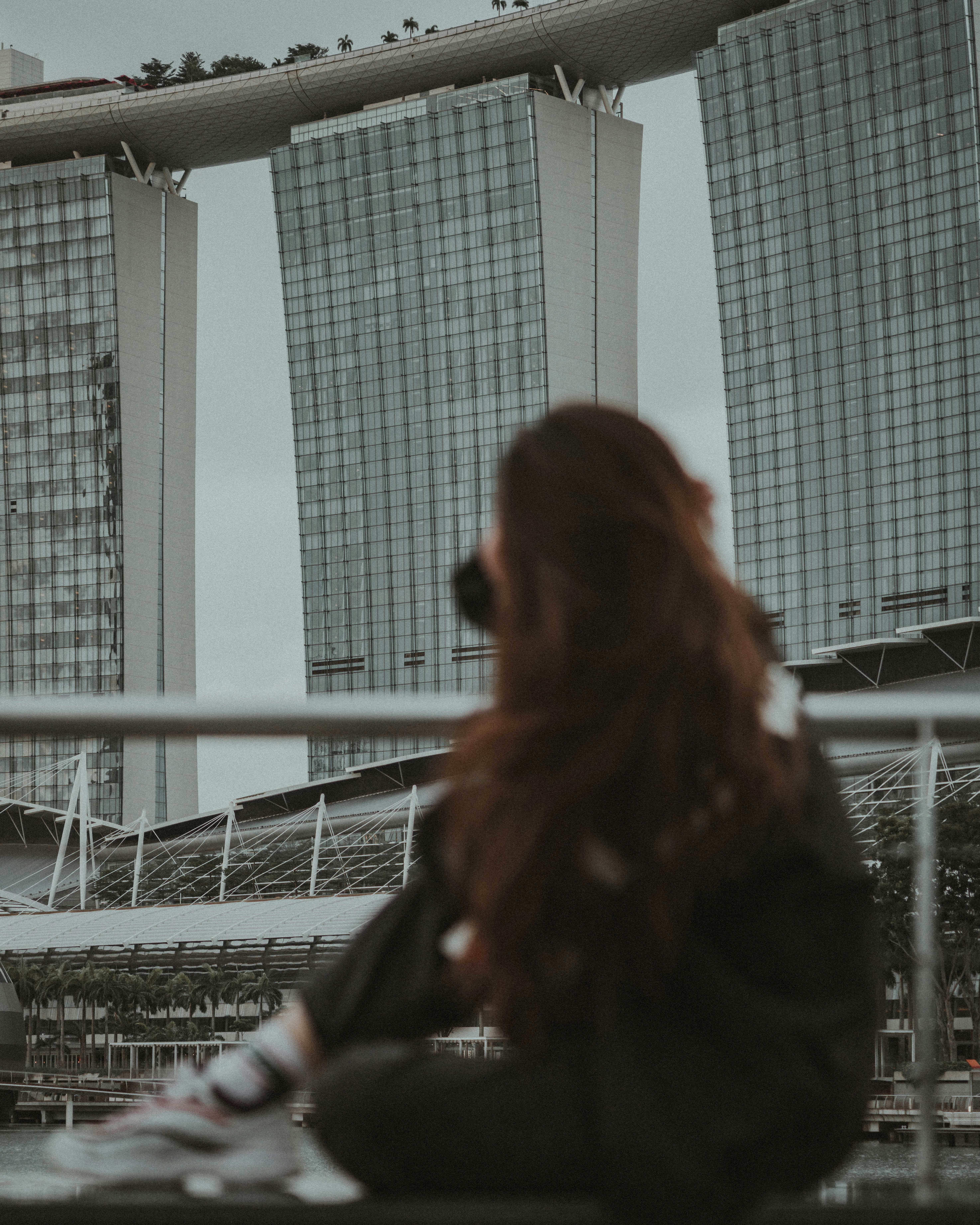 woman in black jacket standing near white metal fence