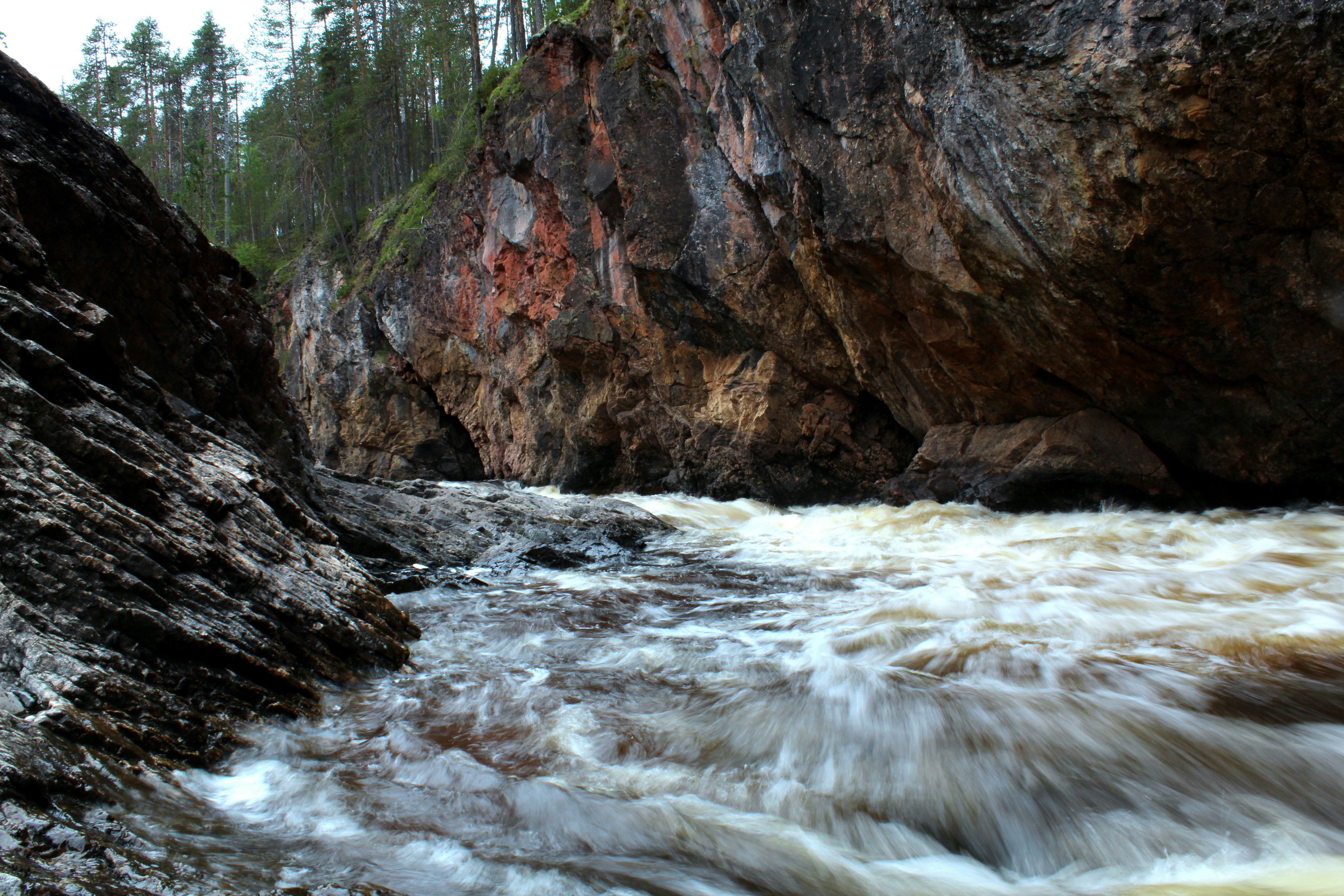 brown rocky mountain beside river during daytime