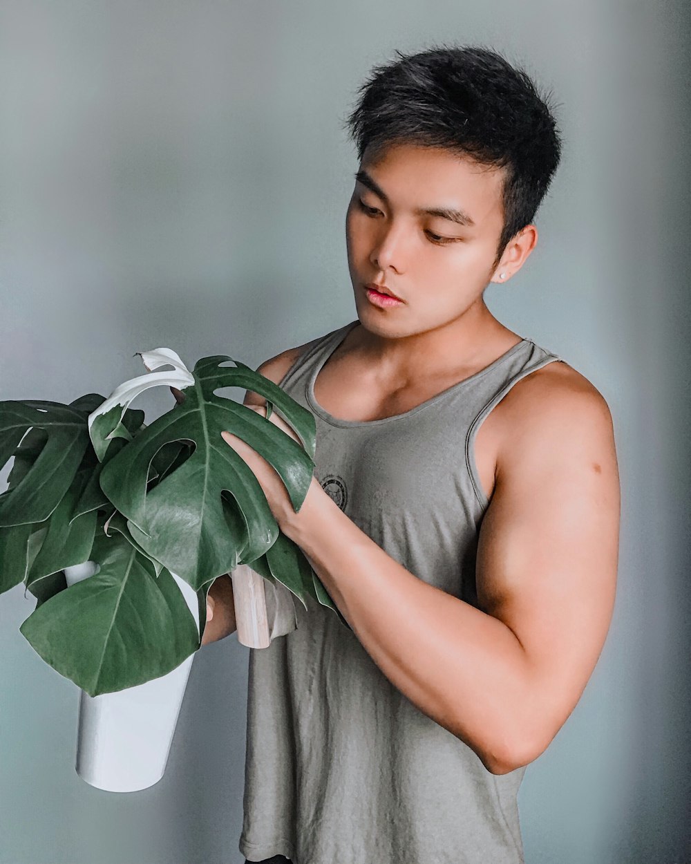 woman in gray tank top holding green plant