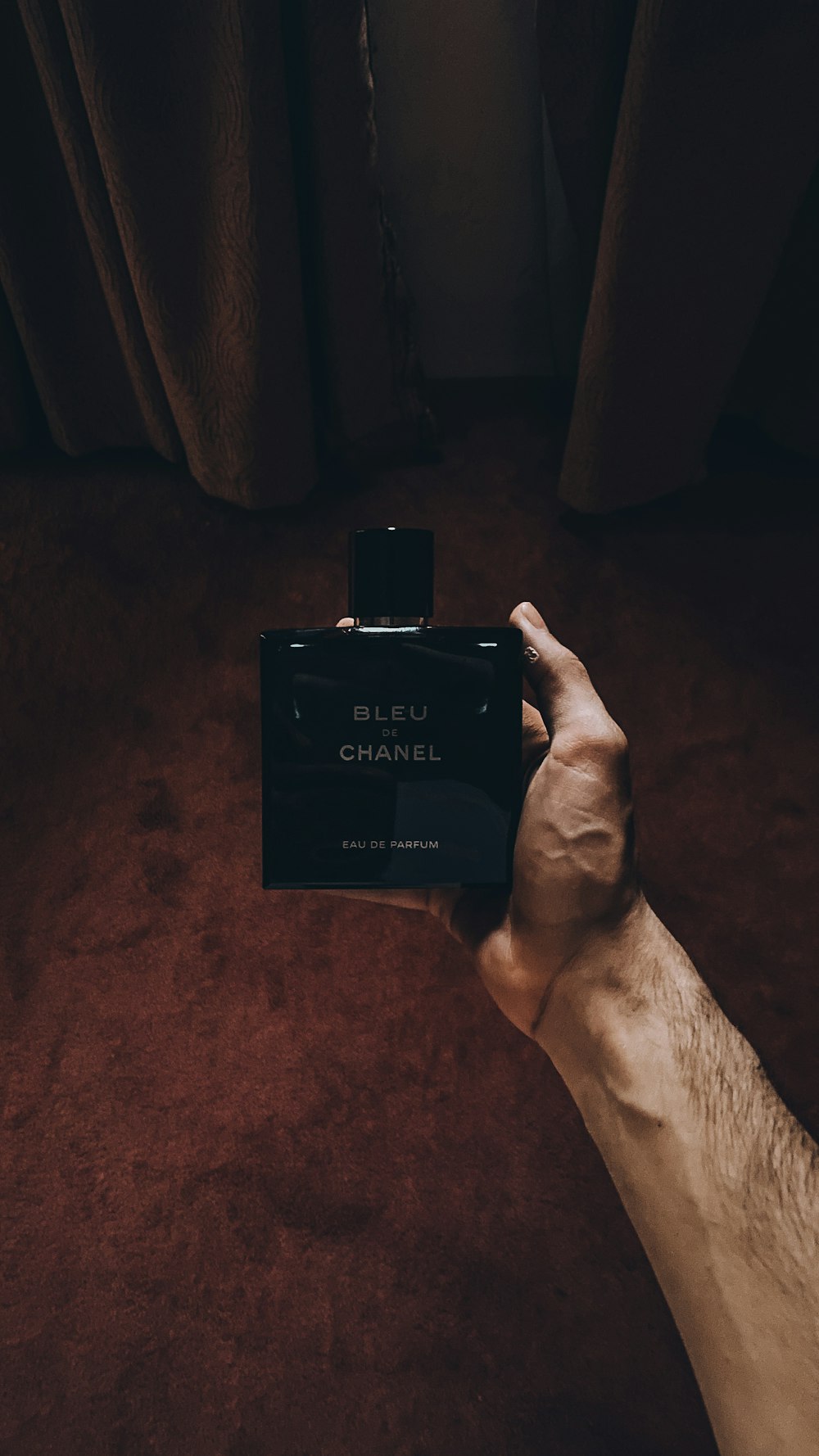 Persona che tiene la bottiglia di profumo nera di Calvin Klein