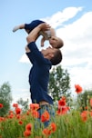 man in blue long sleeve shirt carrying baby in white onesie