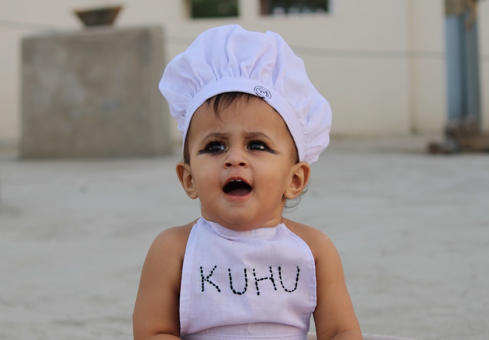 baby in white tank top and white cap