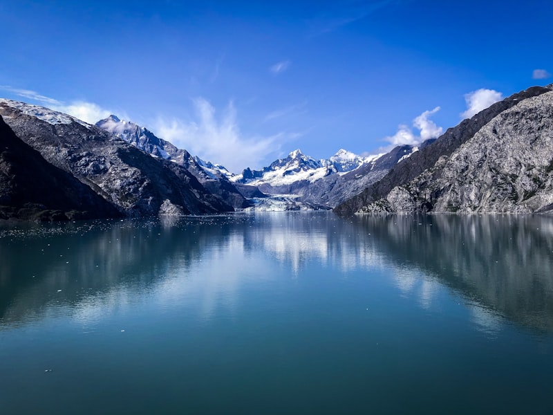 Calm Glacier Bay fjord with snow-capped mountains reflected in the water on an Alaska cruise