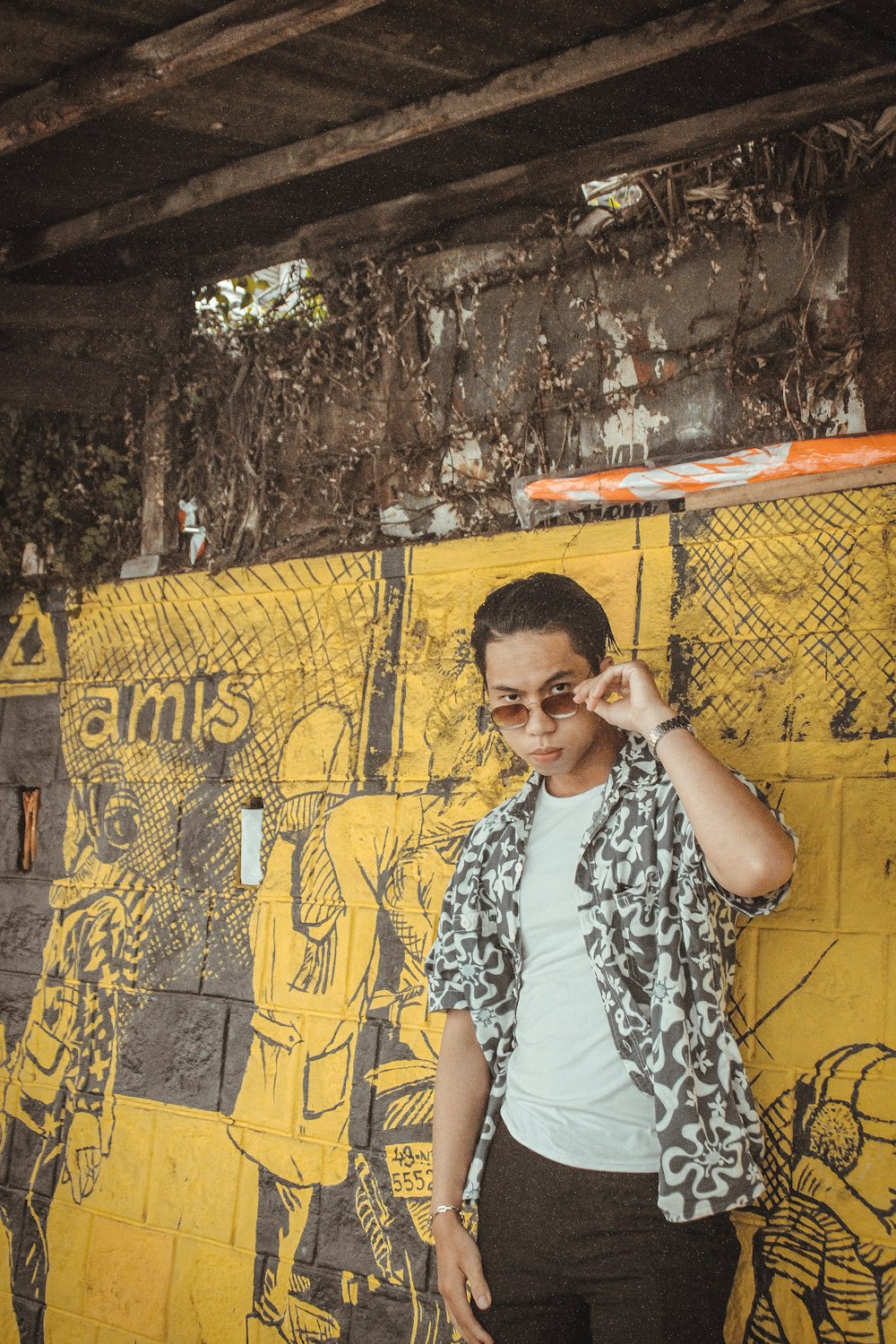 man in white and black crew neck t-shirt sitting on yellow and black concrete wall