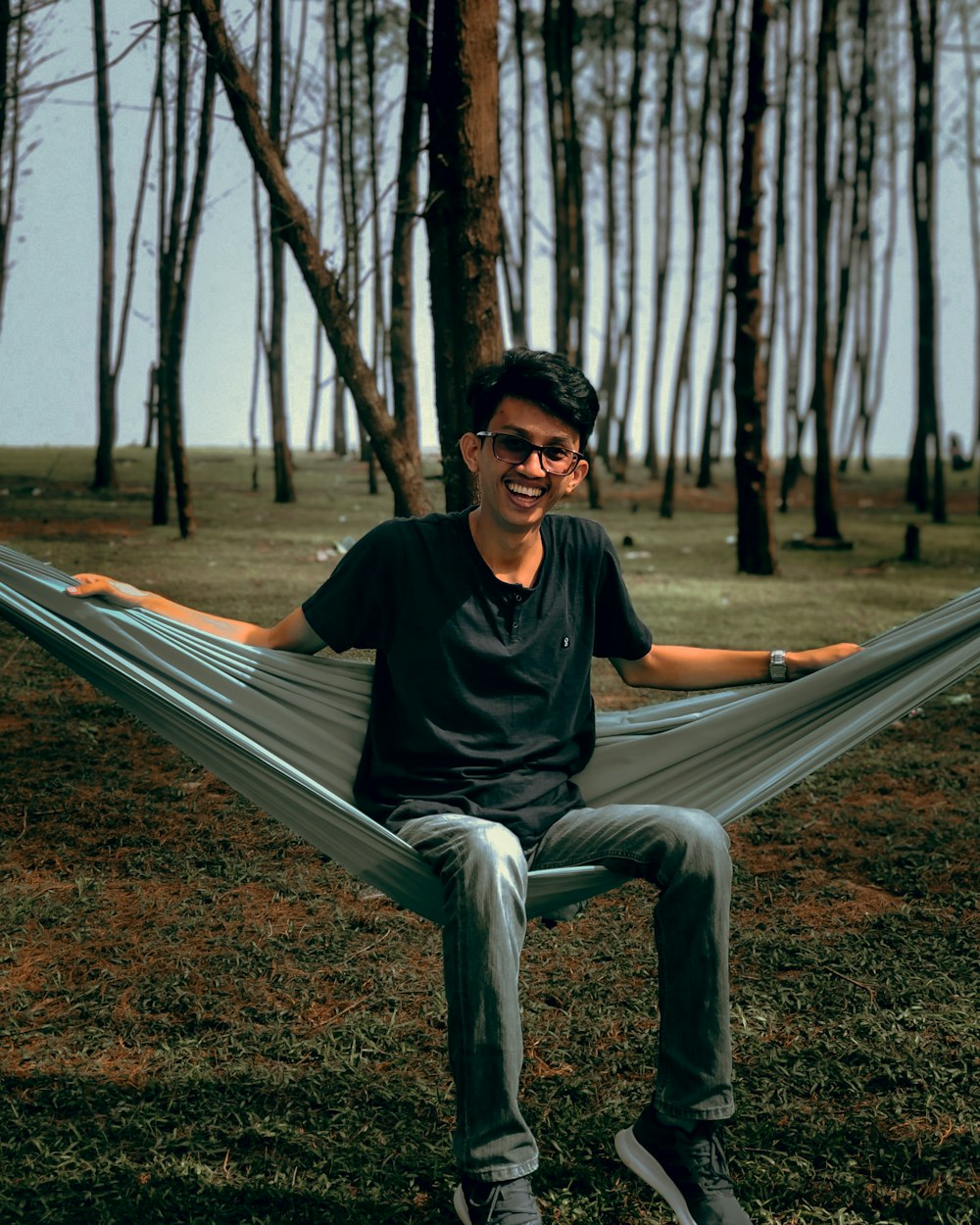 man in black crew neck t-shirt sitting on gray wooden bench