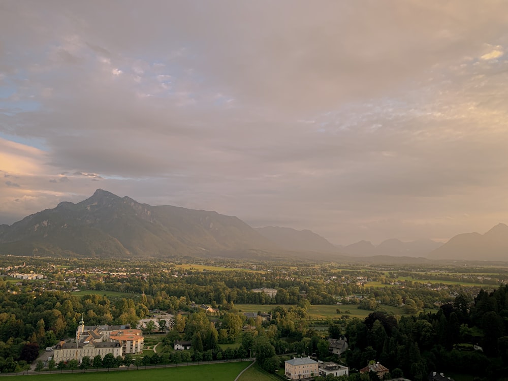 green trees and mountains under white clouds during daytime