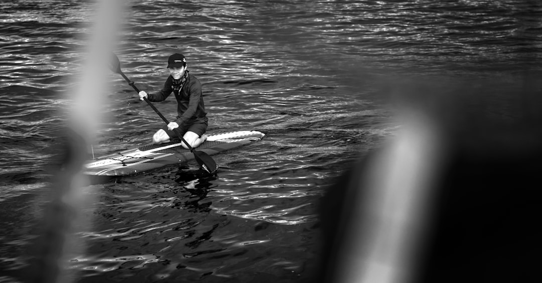 man in black jacket riding on white kayak on body of water