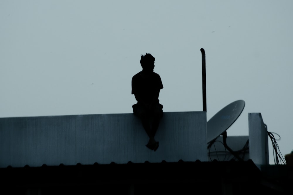 man in black jacket and pants standing on top of building