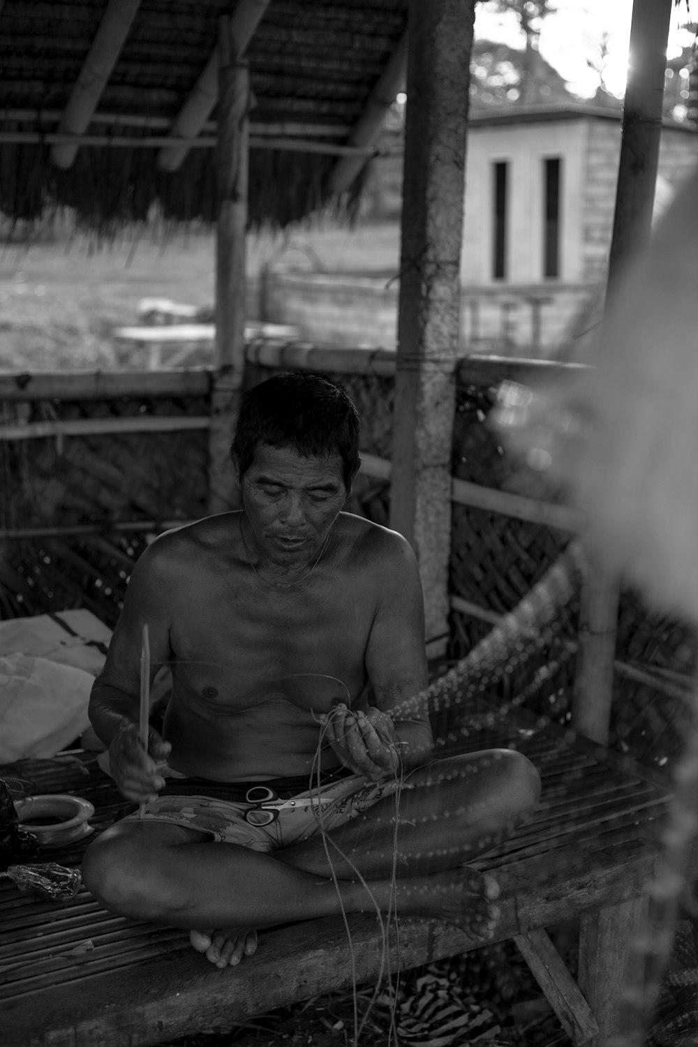 topless man sitting on wooden bench