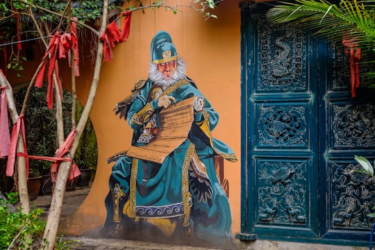 man in brown and beige robe holding red and white stick statue in China House Malaysia