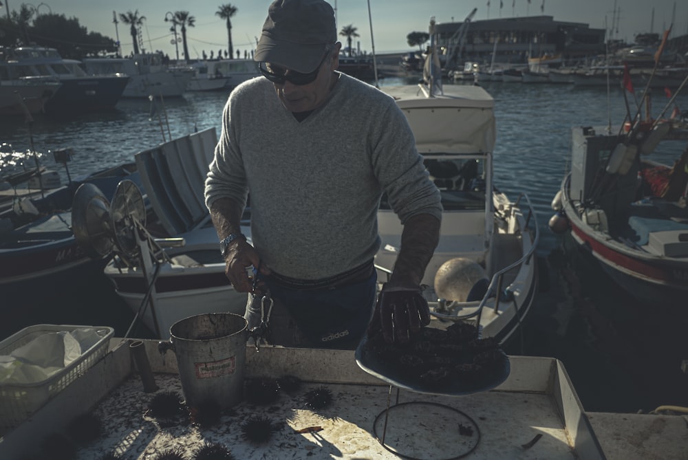 man in white sweater and black pants standing near body of water during daytime