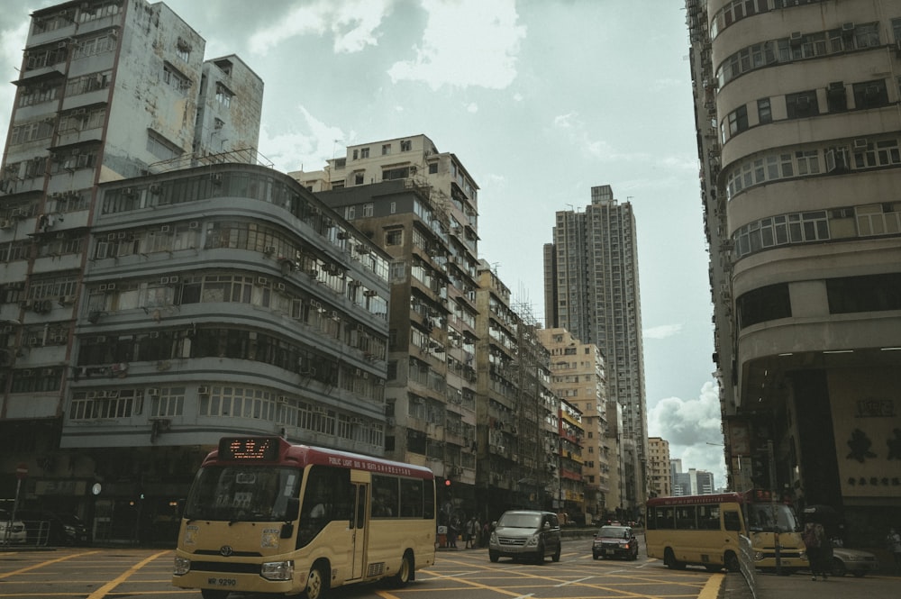yellow bus on road near high rise buildings during daytime