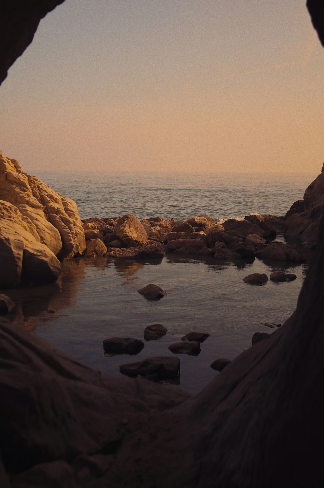 brown rocky mountain beside body of water during sunset