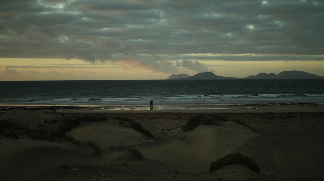 person standing on beach shore during sunset