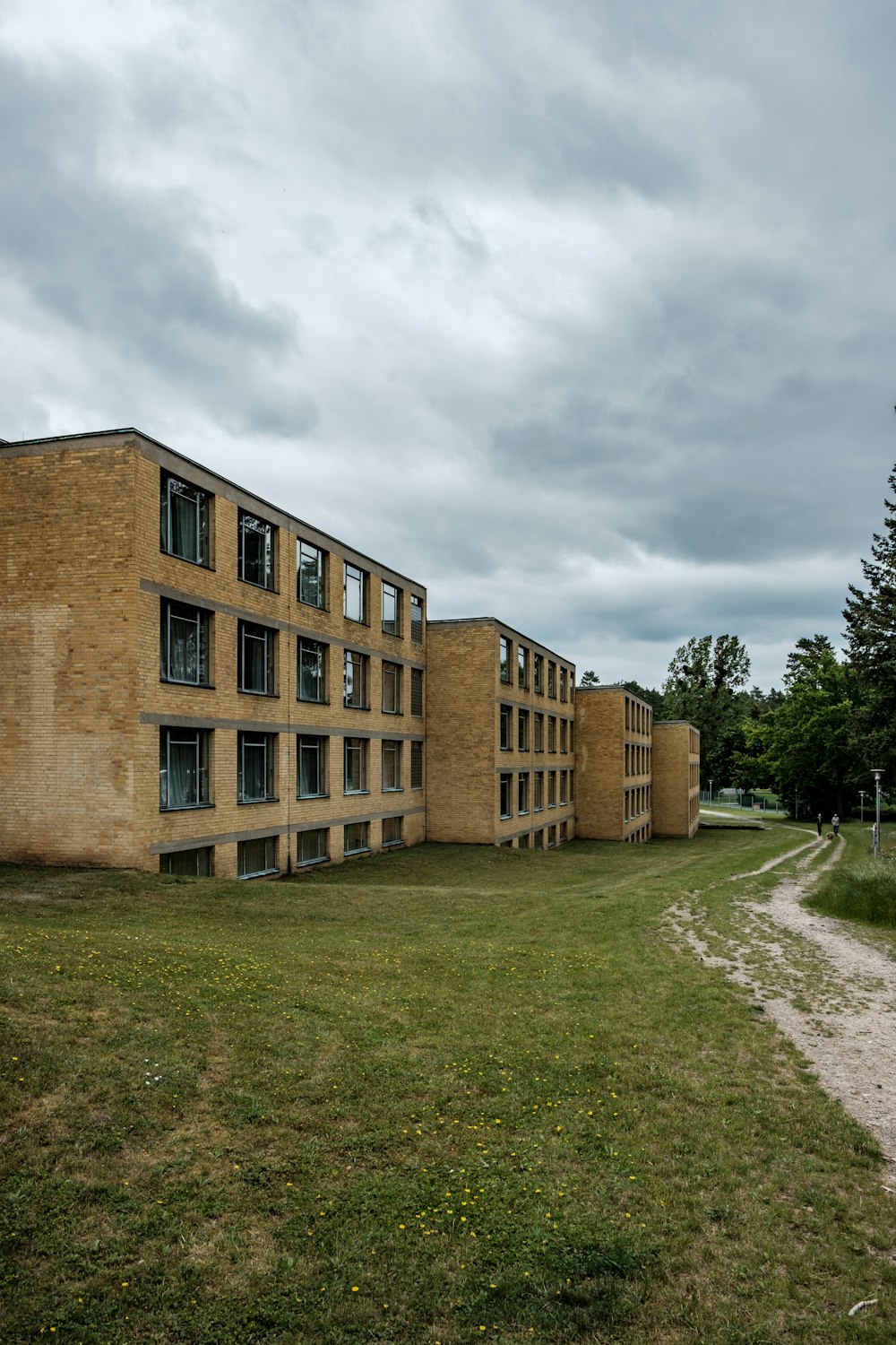 Edificio de hormigón marrón cerca de un campo de hierba verde bajo un cielo nublado durante el día