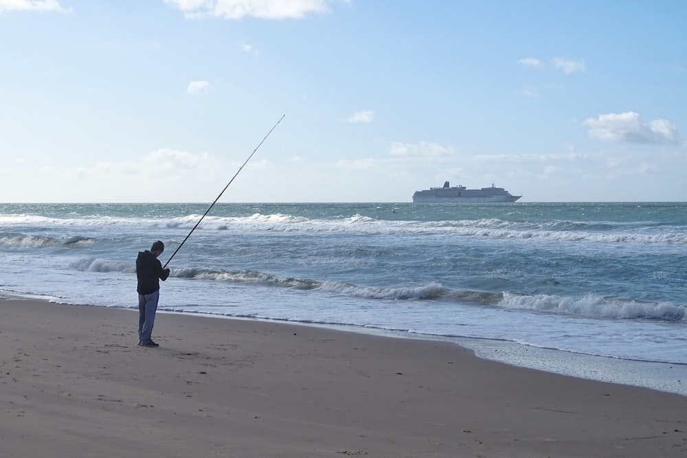 man in black shirt fishing on beach during daytime