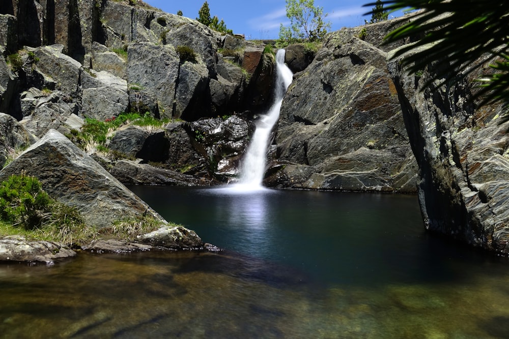 waterfalls between gray rocky mountain during daytime