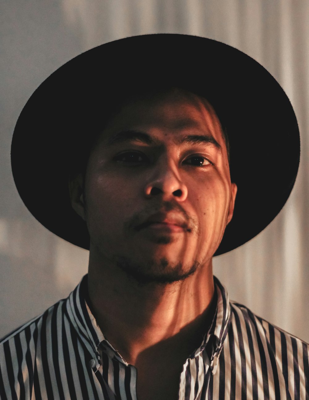 man in black and white striped shirt wearing black hat