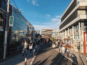 A bustling city street scene with people engaging in daily activities under bright sunlight.