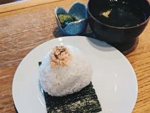 Close-up of freshly made onigiri wrapped in crisp nori, resting on a wooden board