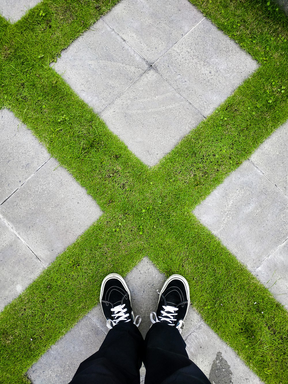 person in black and white sneakers standing on gray concrete pavement