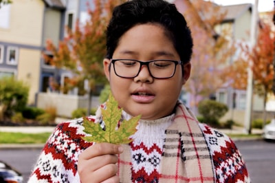 A cheerful student on campus holding books with Canadian flag colors.