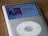 A silver iPod Classic displaying a music track on its screen. The track is titled 'Fantastic Man' by William Onyeabor from the album 'World Psychedelic Classics'. The album art features a person in a suit and hat against a red background.