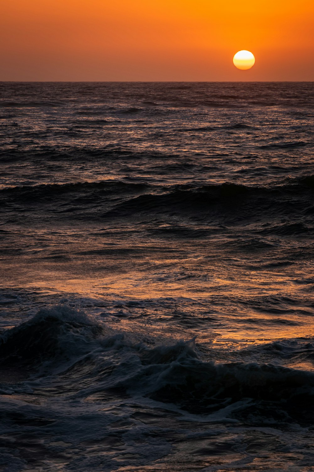 ocean waves crashing on shore during sunset