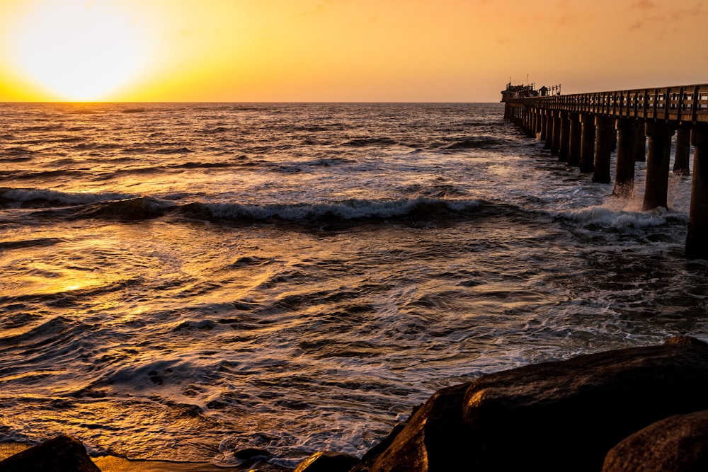 sea waves crashing on beach dock during sunset