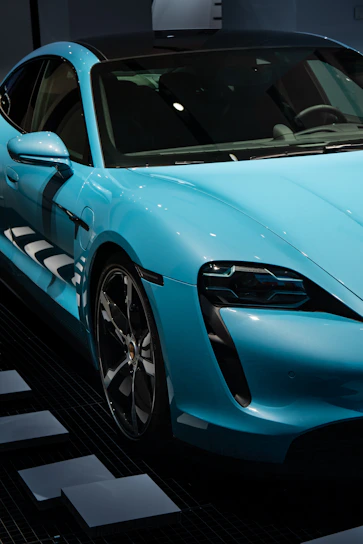 A sleek blue sports car gleaming under bright studio lights, highlighting its aerodynamic curves.