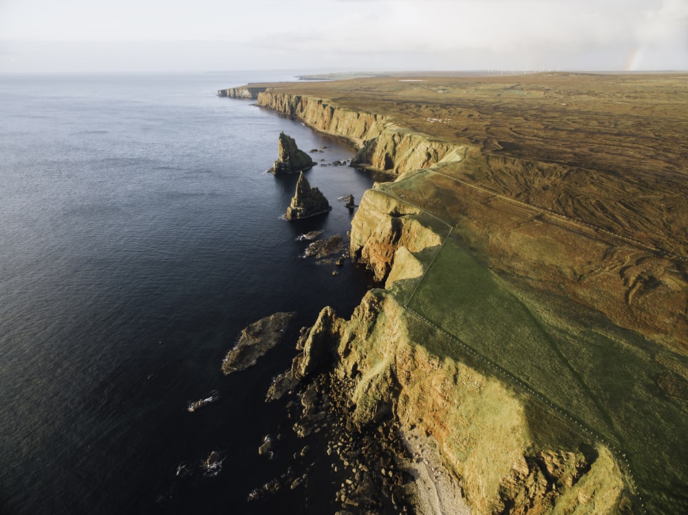 aerial view of green and brown mountain beside sea during daytime