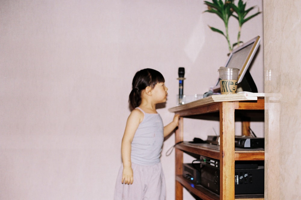 woman in white tank top and white skirt standing beside brown wooden table