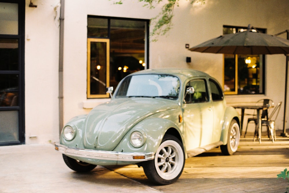 white classic car parked beside white concrete building