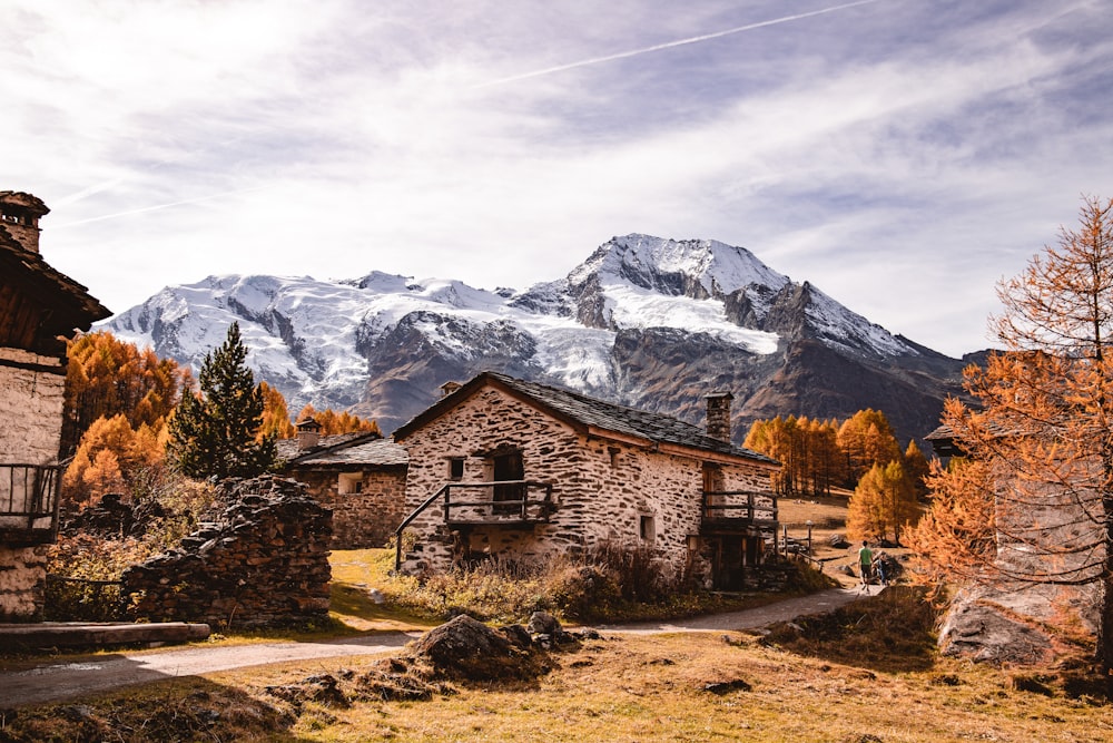 Maison en bois marron près d’une montagne enneigée pendant la journée