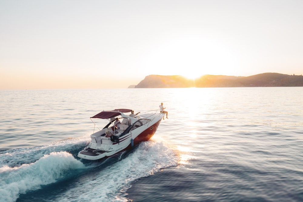 homme équitation sur un bateau blanc et rouge sur la mer pendant la journée