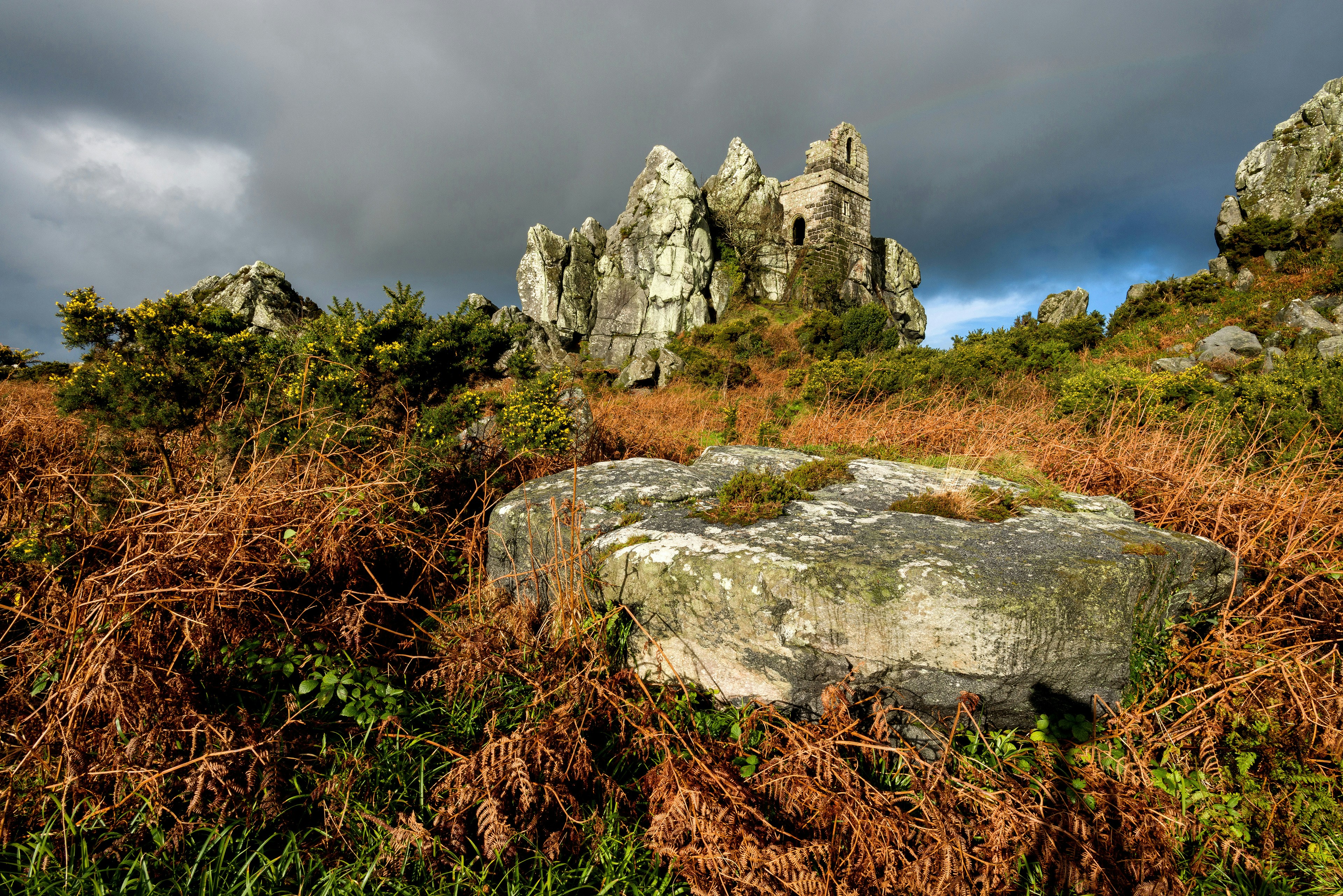 gray rock formation on green grass field under gray cloudy sky during daytime