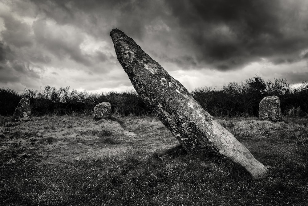 gray rock on green grass field under gray clouds