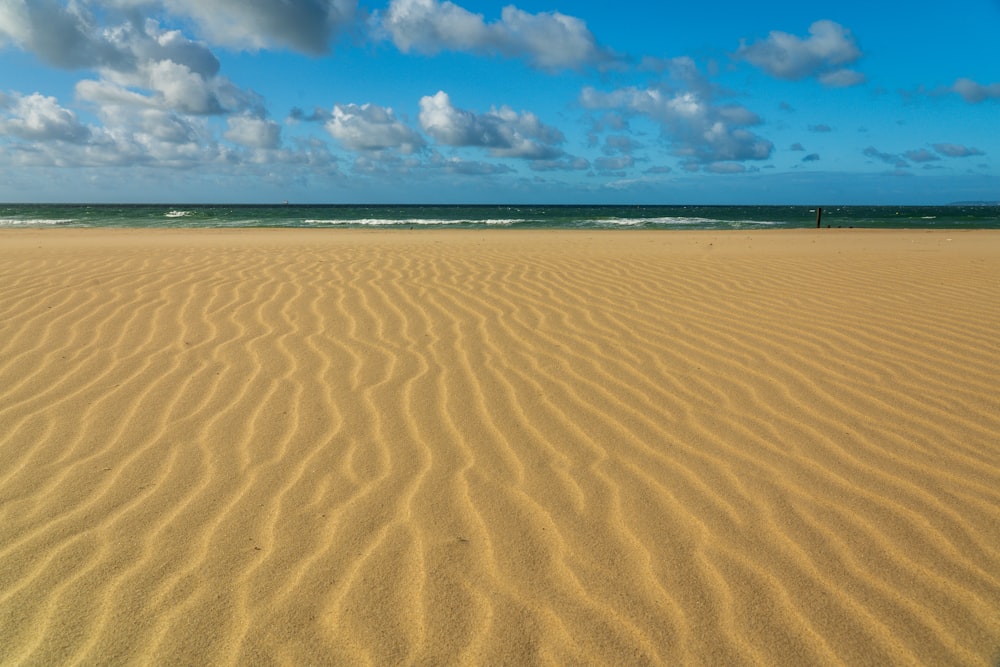 brown sand under blue sky and white clouds during daytime