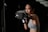 A woman in athletic wear is intensely focused as she throws a punch, wearing boxing gloves. Her stance and expression suggest concentration and determination. The background is dark, emphasizing her figure and action.