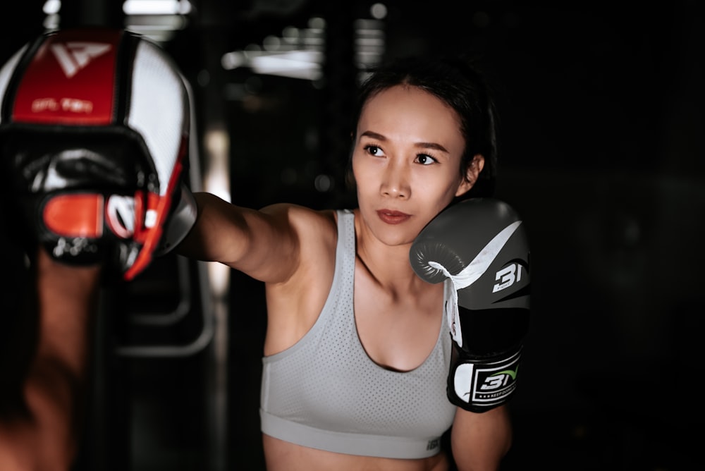 woman in gray sports bra and black and white nike boxing gloves