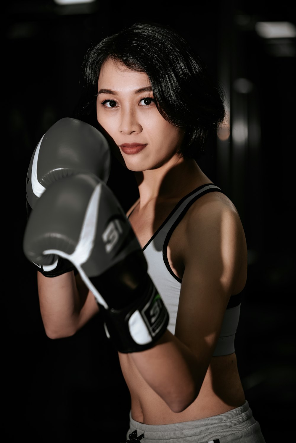woman in black and white nike tank top wearing black boxing gloves