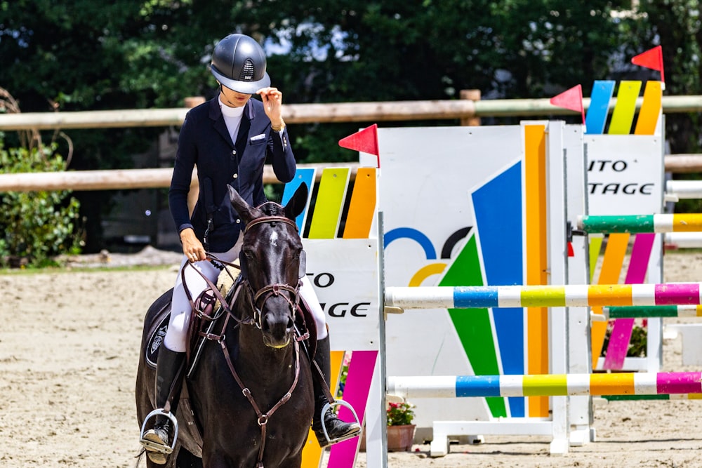 homme en veste en cuir noir chevauchant un cheval brun pendant la journée